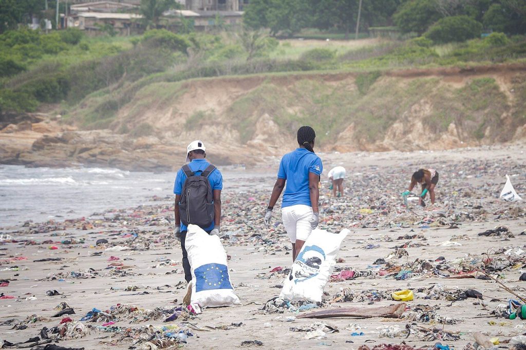 Volunteers carrying bags of plastic waste collected from a beach in Ghana