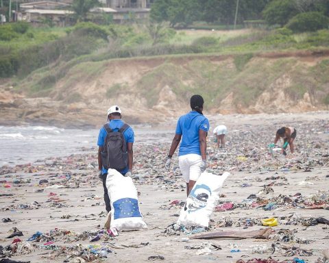 Volunteers carrying bags of plastic waste collected from a beach in Ghana