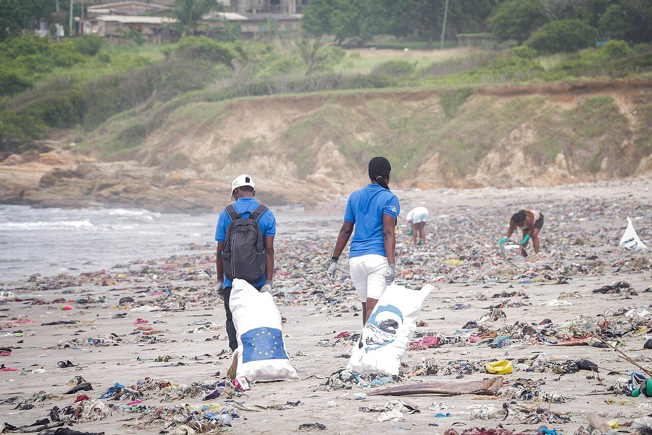 Volunteers carrying bags of plastic waste collected from a beach in Ghana